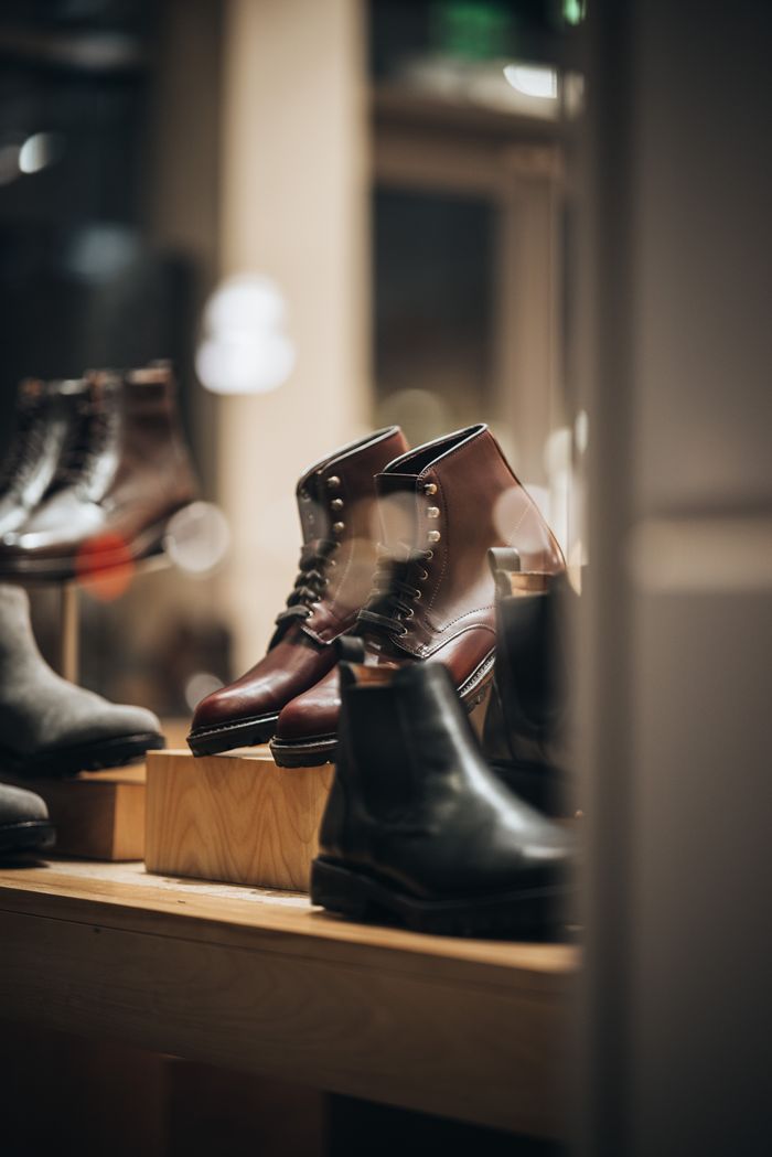 services-04 A stylish storefront display featuring a variety of elegant leather boots, perfect for fashion-forward individuals.