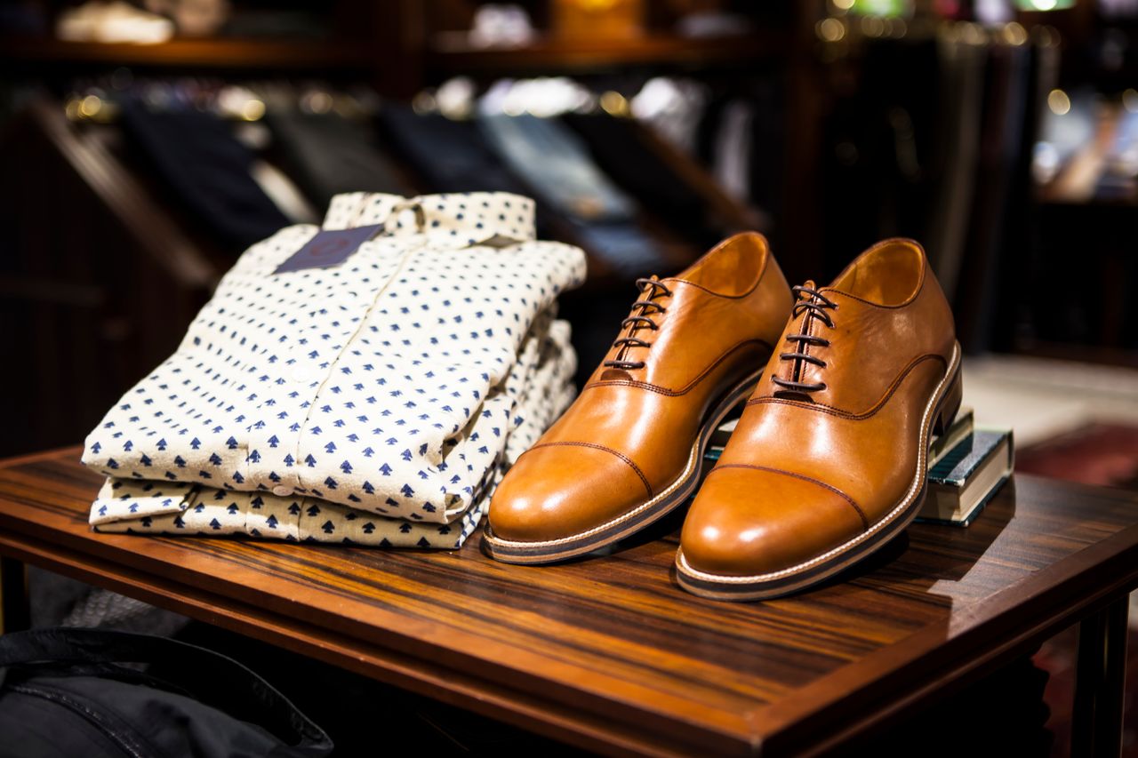 The Art of Drawing Readers In: Your attractive post title goes here Elegant brown leather shoes and printed shirt displayed on a wooden table in a stylish clothing store.