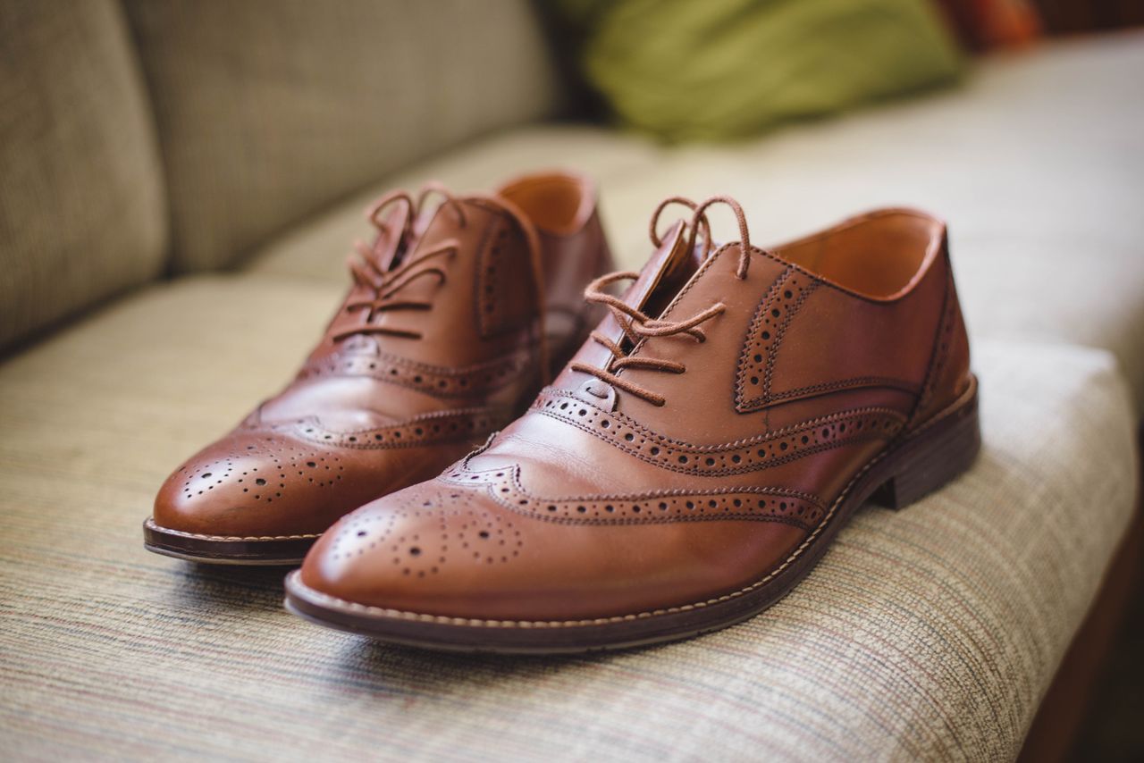 our-story Elegant brown pair of leather shoes for men placed on gray surface at home